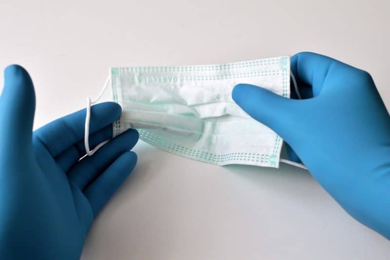 A surgical mask held by a person wearing gloves