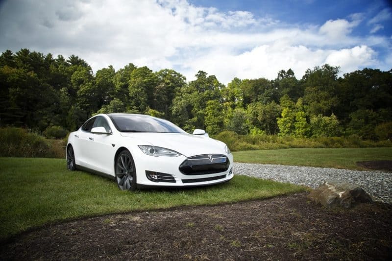 a white Tesla vehicle with trees in the background